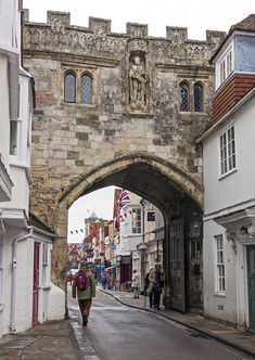 a man walking down a street under an arch