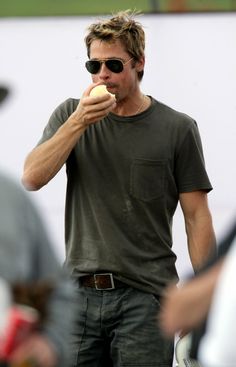 a man eating an apple while wearing sunglasses