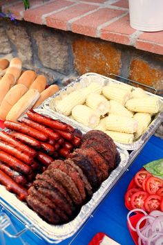 hotdogs, corn on the cob and other foods are displayed in trays