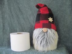 a toilet paper holder with a gnome's head next to a roll of toilet paper