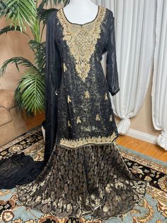 Ready to wear can ship same business day. Color     Black and gold  Fabric    shirt, dupatta (chiffon)                 Inner banarsi jamavar and also a soft                  Layer underneath                  Sharara fabric Banarsi chiffon  Embroidery details  Total handmade adda work Kora, Dabka, Stones, Pearls The fabric used in this dress is very high quality. Embroidery is very elegant and neat and gives designer dress. Very high quality nicely stitched stylish sharara suit. Size Large  Shoulder 17 Chest 22 Waist 21 Hips 23 Shirt length 35 Sharara length 44 This dress is available in size  large  ready to wear and  can ship immediately. if you need same dress in other sizes  can be made to your size contact me 818-687-2408  for your customize size. Thanks Elegant Shantoon Sets With Zari Work, Elegant Shantoon Sharara For Festive Occasions, Semi-stitched Gold Chanderi Lawn Suit, Gold Floor-length Sharara For Transitional Season, Elegant Gold Georgette Lehenga, Elegant Party Sharara In Shantoon, Elegant Traditional Wear With Zari Work In Shantoon, Elegant Shantoon Traditional Wear For Festive Occasions, Elegant Shantoon Sharara With Zari Work