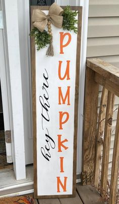 a wooden sign that says pumpkin on the side of a house with an orange bow