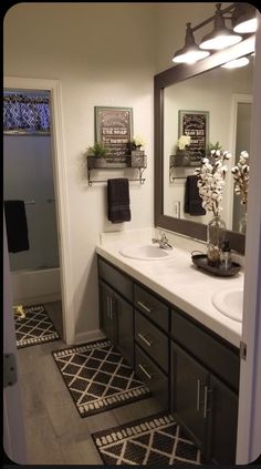 a bathroom with black and white rugs on the floor, two sinks and mirrors