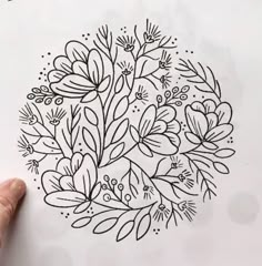 someone is drawing flowers in the middle of a page with black and white ink on paper