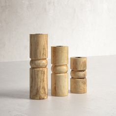 three wooden candlesticks sitting on top of a white table next to each other