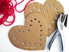 two heart shaped paper cut out with scissors and yarn on the table next to it