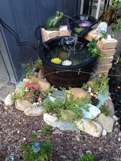 an outdoor fountain surrounded by rocks and plants