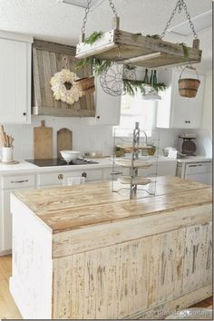 a kitchen with an island made out of wooden planks and hanging baskets on the ceiling