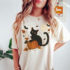 Our black cat halloween shirts are the perfect wear for the fall season and the Halloween party! These shirts are unisex fit.Please use the measurements chart in the pictures section to determine your correct size. Please Size up for an oversized look. Lay your favorite shirt at home flat and measure armpit to armpit to compare to the size chart in the photos Rolled Sleeves in pictures is for styling purposes only . Props used In photos are NOT included with purchase. Care Instructions: Wash inside out in warm water, gentle cycle, tumble or line dry. Do not iron on design. https://www.etsy.com/shop/ModishChicBoutique?ref=seller-platform-mcnav If you have any questions, please contact me and I will be happy to answer. Please note that due to lighting effects, monitor's brightness, contrast Bohemian Picnic, Pumpkin Cat, Chic Maxi Dresses, Butterfly Blouse, Pumpkin Print, Pumpkin Shirt, Floral Midi Skirt, Cat Shirt, Fall Shirt