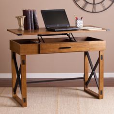 a laptop computer sitting on top of a wooden desk in front of a brown wall