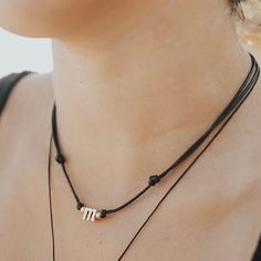 a woman wearing a black and white necklace with two letters on the bottom of it