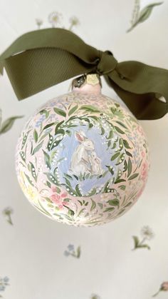 an ornament with a green ribbon hanging from it's side on a wall