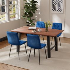 a dining room table with blue chairs and a potted plant in the corner next to it