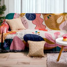 a living room with a couch covered in a colorful blanket and two pillows on top of it