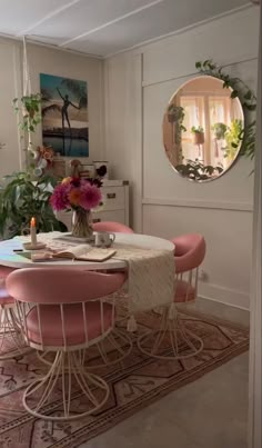 a dining room table with pink chairs around it