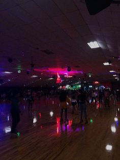 many people are dancing on the dance floor in a large room with lights all around