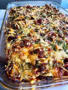 a casserole dish with cheese, tomatoes and other toppings in a glass baking dish