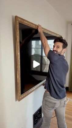 a man standing in front of a flat screen tv with his hands on the wall