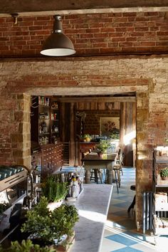 an open kitchen and dining area with brick walls, flooring and potted plants