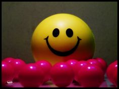 a yellow ball with a smiley face surrounded by pink balls