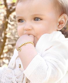 a baby wearing a white sweater and gold bracelet