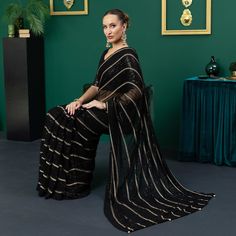 Introducing the bewitching Damia, a saree so enchanting, it will leave you spellbound. In shimmering black chiffon, this pre-pleated saree is adorned with intricate threadwork and twinkling sequins that shimmer with every step you take. Dazzling from every angle, the short net blouse glitters with an array of sequins, while the deep back of the blouse features sultry tassels that add a touch of allure to the look. The 3/4 semi-sheer sleeves add a hint of subtle grace to this striking ensemble. The black silk petticoat provides an ideal canvas for the saree, allowing its bewitching beauty to truly stand out. Indulge in the magic of Damia and captivate all those around you. Saree:  Color: Black  Fabric: Chiffon Preplated sari with sequins and threadwork all over  Short net blouse with sequin Elegant Black Pre-draped Saree With Zari Work, Black Sequined Pre-draped Saree, Glamorous Black Pre-draped Saree, Elegant Black Saree For Eid, Elegant Black Pre-draped Saree For Evening, Chiffon Pre-draped Saree With Sheer Dupatta For Party, Elegant Black Saree For Diwali, Black Saree Blouse Piece For Eid, Black Pre-draped Saree With Sheer Dupatta