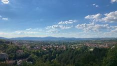 a scenic view of a city with mountains in the distance and trees on either side