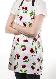 a woman wearing an apron with cherries on it and her arms crossed in front of her chest