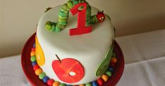 a birthday cake with the number one on it, decorated in candy and caterpillars