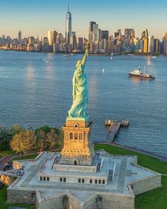 the statue of liberty stands in front of a large body of water with a cityscape in the background