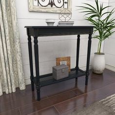 a living room with a potted plant on the floor and a black console table