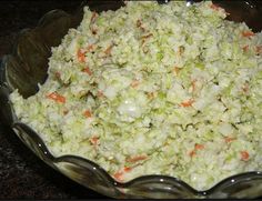 a glass bowl filled with coleslaw and carrots on top of a table