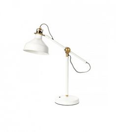 a white and gold desk lamp on a white surface with a cord attached to it