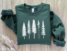 The coziest pine tree sweatshirt, perfect for camping and hiking trips in the forest! MATERIAL ✨ Sweatshirt sizes are Unisex, please refer to sizing chart in listing photos ✨ 50% cotton, 50% polyester ✨ Medium fabric weight PRINTING ✨ DTG Printed  CARE ✨ Machine wash: warm (max 40C or 105F) ✨ Do not iron ABOUT My love for design and clothing is what inspired the creation of this store.  During lockdown, I had so much free time and I have always had a dream to start my own business, and from this Green Winter Sweatshirt For Outdoor Activities, Green Long Sleeve Sweatshirt For Outdoor Activities, Winter Adventure Cotton Sweatshirt, Green Crew Neck Top For Camping, Green Cotton Outdoor Sweatshirt, Green Cotton Sweatshirt For Outdoor, Green Fall Sweatshirt For Outdoor Activities, Green Sweatshirt For Fall Outdoor Activities, Green Sweatshirt For Outdoor Fall Activities