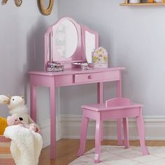 a child's pink vanity table and stool with mirror on the wall above it