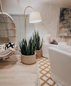 a living room filled with furniture and a plant in a basket on top of the floor