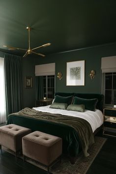 a bedroom with dark green walls and white bedding, two foot stools on the floor