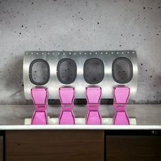 four pink chairs sitting on top of a counter in front of a metal wall mounted device