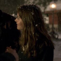 a man and woman standing in the snow looking into each other's eyes,