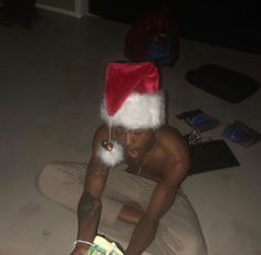 a man wearing a santa hat sitting on the floor with money in his hand and looking at it