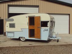 an old trailer parked in front of a garage