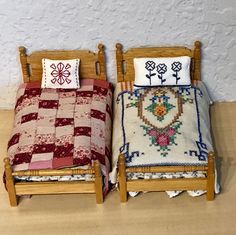 two miniature beds with matching pillows on them