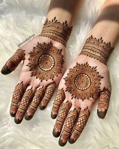 two hands with henna tattoos on them, one is showing the intricate pattern and the other