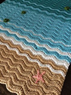 a crocheted blanket with starfish and waves on the bottom is laying on a wooden floor