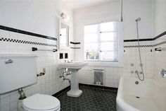 a bathroom with black and white tile flooring, toilet, sink and bathtub