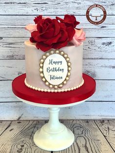 a white and red birthday cake with roses on top