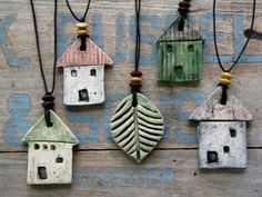 several small wooden houses hanging from strings on a wood wall with green and white paint