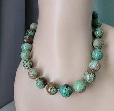 "Lovely Large Round(18-19mm) Natural Turquoise Bead Necklace!  Each one of these beads is a fine example of natural green turquoise and its color and pattern variety in natural rock.  Notice the unusual brown matrix with the Turquoise. This necklace was made in the White Mountains in Arizona by us from these large beautiful natural turquoise round beads sourced from the Tucson Gem Show (where vendors from all over the world sell their country's natural gemstones.)  These very large 18-19mm round Natural Turquoise Beads are polished to a beautiful finish.  We've added tiny Sterling Silver Spacer Beads between each wonderful bead so that the necklace drapes appropriately as you move. Easy to use Sterling Silver adjustable soldered extender chain and Sterling Silver lobster claw enhances the Turquoise Jewelry Western, Tucson Gem Show, Jewelry Western, Western Turquoise, Gem Show, Turquoise Bead Necklaces, White Mountains, Natural Rock, Green Turquoise