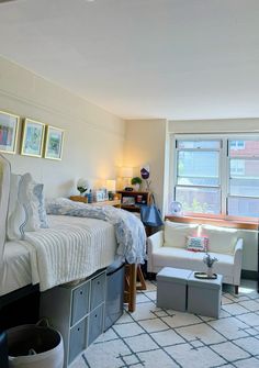 a bed room with a neatly made bed next to a chair and desk in front of a window