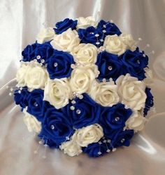 a bridal bouquet with white and blue flowers on it's side, sitting on a shiny surface